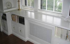 This window seat, while functional and beautiful by itself, also houses a two bookshelves, six file drawers, and the room's heat source.